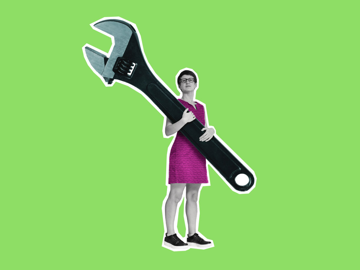 Small woman carrying a large wrench